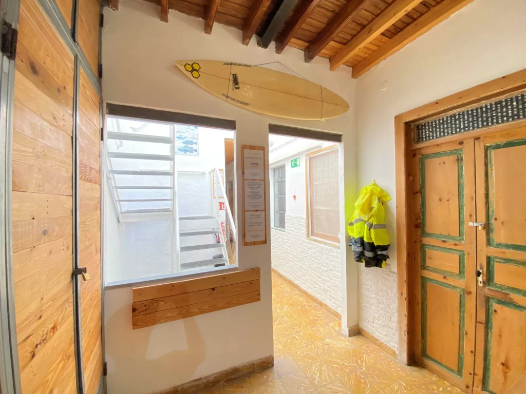 Small living room in EcoIsleta Coliving in the first floor, with space to keep surfboards and doors of the rooms in the first floor.